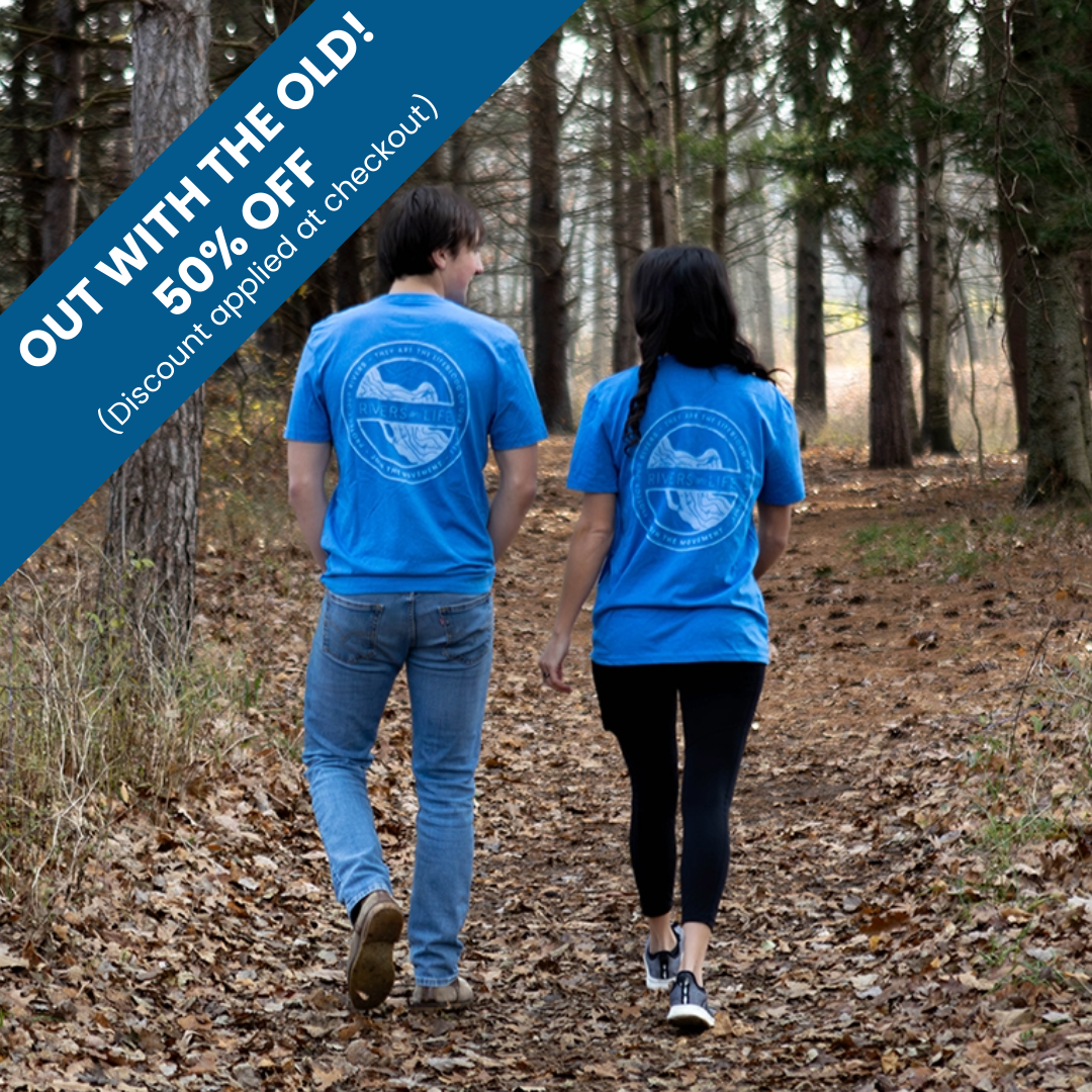 Two people walking in a forest wearing blue Rivers are Life t-shirts.